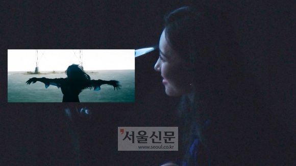 선미가 자신의 신곡 ‘주인공’ 뮤직비디오를 시청하며 미소를 지어보이고 있다.