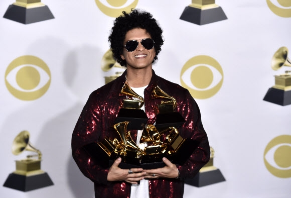 28일(현지시간) 미국 뉴욕 매디슨 스퀘어 가든에서 열린 제60회 그래미 시상식에서 ‘올해의 노래’, ‘올해의 레코드’ 등 6관왕을 차지한 브루노 마스가 기자회견장에 자신이 받은 모든 트로피를 안고 있다.  뉴욕 AP 연합뉴스