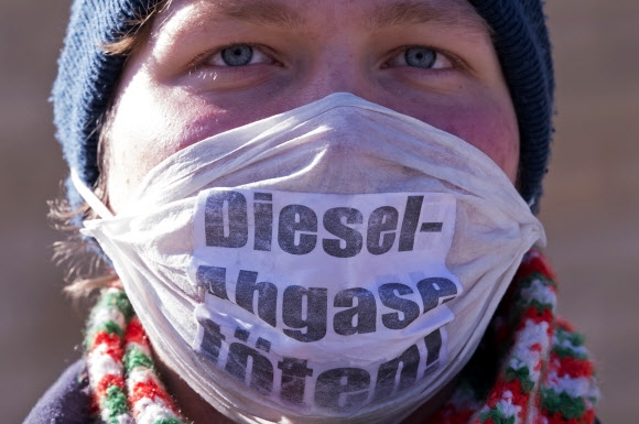 한 환경운동가가 27일(현지시간) 지자체의 디젤차 금지 권한에 대한 판결이 진행 중인 독일 라이프치히 연방행정법원 앞에서 ‘디젤 배출이 (우리를) 죽인다’고 적은 마스크를 쓰고 시위하고 있다.  라이프치히 AP 연합뉴스