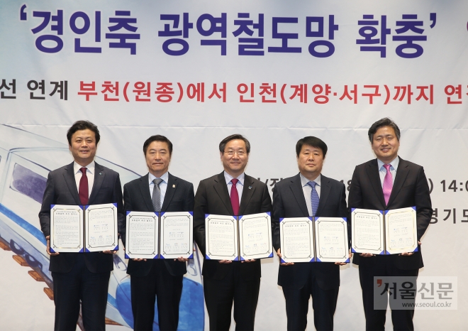 부천시청 판타스틱큐브에서 20일 오후 김만수(왼쪽) 부천시장과 유정복(가운데) 인천시장 등이 참석한 가운데 광역철도 공동추진 업무협약을 하고 협약서를 들어보이고 있다. 부천시 제공