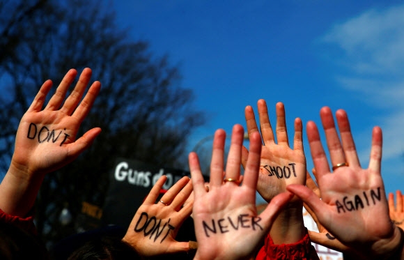 집회 참가자들이 ‘쏘지 마세요’ 등 총기 규제를 촉구하는 메시지를 적은 손바닥을 펼쳐 보이고 있다.  워싱턴 로이터 연합뉴스