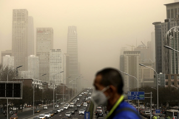 숨 막히는 中 베이징 28일 마스크를 쓴 한 남성 너머로 중국 베이징 시내가 먼지에 뒤덮여 있다. 이날 몽골에서 온 미세먼지와 모래가 베이징을 강타하면서 뿌연 안개에 휩싸인 것처럼 건물이 제대로 보이지 않는다.  베이징 EPA 연합뉴스