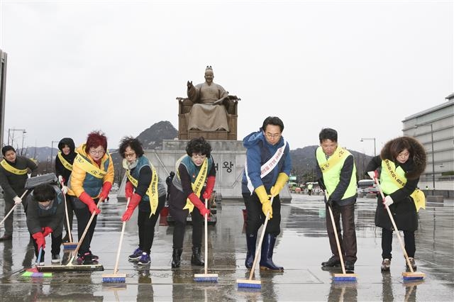 김영종(오른쪽 세 번째) 종로구청장이 지난 21일 구청 직원 및 봉사단체 회원들과 함께 광화문광장 바닥을 빗자루로 물청소하고 있다.  종로구 제공