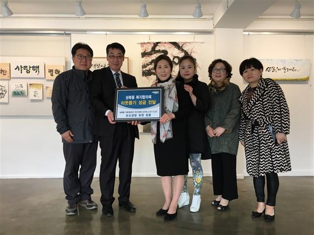 서울 성북구 성북동 작은갤러리에서 무료 전시회를 열게 된 손도공방 회원들이 감사의 표시로 성북동 주민센터 관계자에게 성금을 전달하고 기념사진을 찍고 있다. 성북구 제공