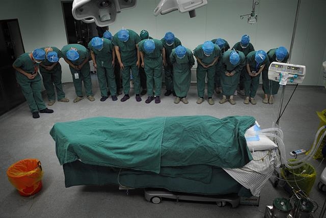 중국 안후이성 허페이의 한 병원에서 의사와 간호사가 장기 기증자의 시신에 목례하고 있다.  출처 sixthtone.com