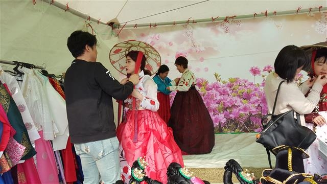 진달래축제장을 찾은 여성들이 진달래 무늬로 장식된 전통 모자를 써 보고 있다.