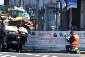 [한 컷 세상] 신문 보는 폐지 줍는 노인