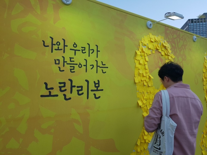 세월호 4주년을 맞은 16일 서울 종로구 광화문 광장에서 열린 4.16 기억 전시장 한편에 마련된 추모 공간에서 한 시민이 추모의 마음을 담은 포스트잇을 붙이고 있다.