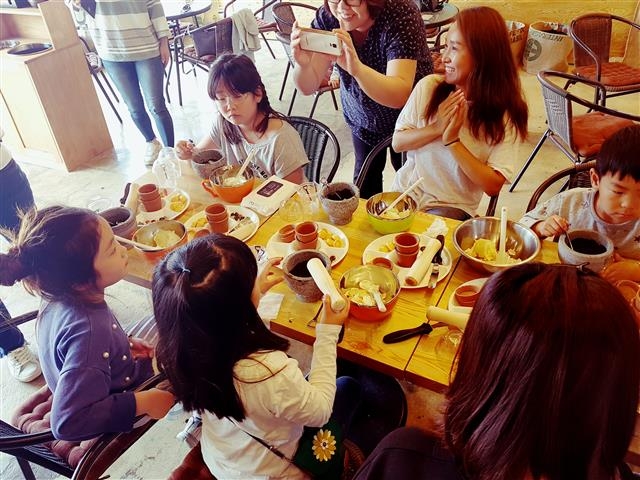 첨단 정보통신기술(ICT)이 접목돼 다양한 첨단 이벤트가 가능한 꽃밭양지 카페에서 관광객들이 감자화분케이크 앙금플라워케이크 만들기 체험을 하며 즐거워하고 있다.  의야지바람마을 제공