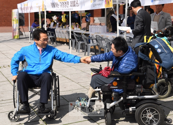 김영종(왼쪽) 서울 종로구청장이 지난 17일 장애인의 날(4월 20일)을 앞두고 대학로 마로니에 공원에서 열린 장애인 행사에서 휠체어 체험 중 다른 참여자와 인사하고 있다.  이호정 전문기자 hojeong@seoul.co.kr