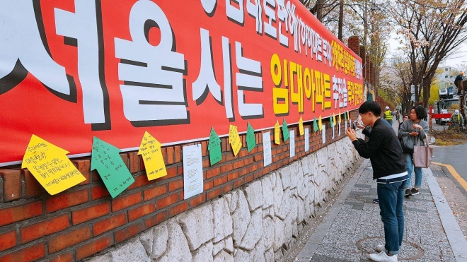 서울 영등포구의 한 아파트 담벼락에 청년임대주택 신축을 반대하는 플래카드가 걸려있다. 민달팽이 유니온 회원들이 플래카드 하단에 청년들의 입장을 대변하기 위한 문구를 붙이는 중이다. 민달팽이 유니온 제공