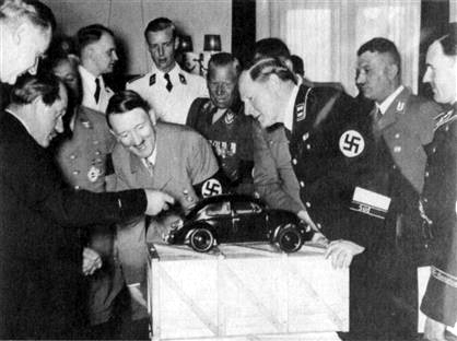 독일의 유명 스포츠카 브랜드 포르셰의 설립자인 페르디난트 포르셰(왼쪽)가 1938년 4월 20일 히틀러(가운데)의 생일을 맞아 히틀러에게 새로운 폭스바겐 모형을 손으로 가리키며 설명하고 있다. 울력 제공