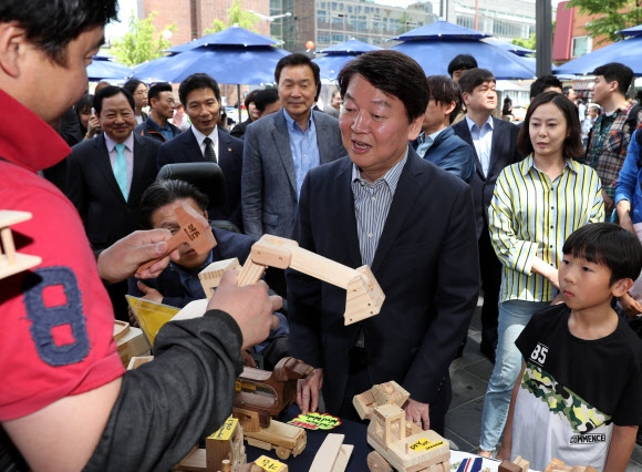 안철수(가운데) 바른미래당 서울시장 후보가 종로구 인사동에서 한 상인의 물건 설명을 듣고 있다.  연합뉴스