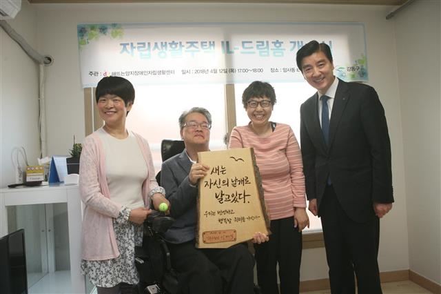 이해식(맨 오른쪽) 서울 강동구청장이 지난달 12일 개소식이 열린 강동구 암사동 장애인 자립생활주택에서 오성섭(왼쪽 두 번째) 해뜨는양지장애인자립생활센터 소장에게 통나무로 만든 현판을 전달한 뒤 기념 촬영을 하고 있다. 강동구 제공