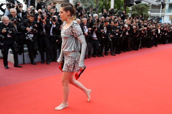 영화배우 크리스틴 스튜어트가 14일(현지시간) 프랑스 칸에서 열리고 있는 ‘제71회 칸 국제영화제(Cannes Film Festival)’ 중 영화 ‘블랙클랜스맨(BlacKkKlansman)’ 시사회에서 하이힐을 벗고 맨발로 레드카펫 위를 걷고 있다.<br>AFP 연합뉴스