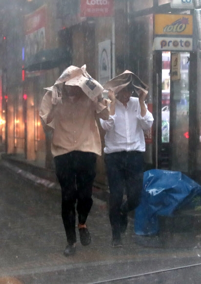 서울 등 수도권 지역에 장맛비와 같은 폭우가 쏟아진 16일 서울 한 도로에서 시민들이 발걸음을 서두르고 있다.  연합뉴스