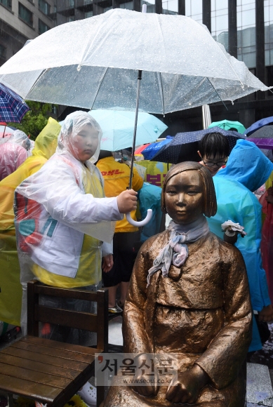 16일 오전 서울 종로구 중학동 일본대사관 앞에서 열린 제1335차 일본군성노예제 문제 해결을 위한 정기 수요시위에 참가한 학생이 우산으로 소녀상을 씌워주고 있다. 도준석 기자 pado@seoul.co.kr