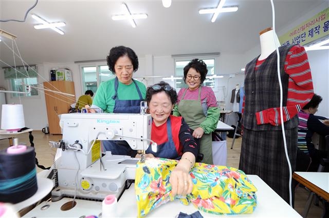 서울 동대문구의 너나들이 공동작업장 1호점에서 어르신들이 재봉틀 앞에서 포즈를 취하고 있다.  동대문구 제공