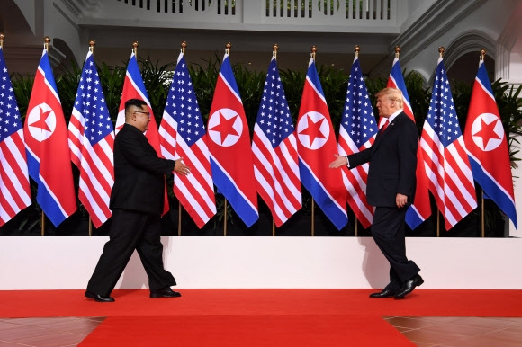 도널드 트럼프(오른쪽) 미국 대통령과 김정은 북한 국무위원장이 12일 오전 센토사섬 카펠라호텔에서 레드카펫 위를 마주 보고 걸으며 악수하고자 손을 내밀고 있다.  싱가포르 AFP 연합뉴스
