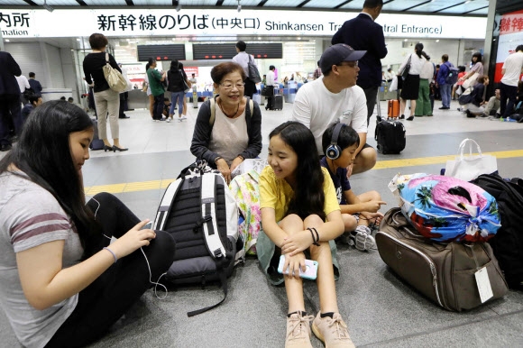 18일 오전 일본 오사카에서 규모 5.9로 추정되는 지진이 발생해 신칸센 운행이 중단된 가운데 여행객들이 바닥에 앉아 열차 운행 재개를 기다리고 있다. AFP 연합뉴스