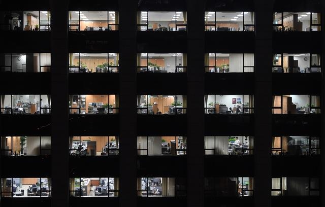 야근하는 직원들을 위해 사무실마다 조명등이 환하게 켜진 서울 광화문의 한 빌딩.  서울신문DB