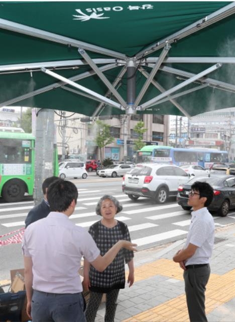 21일 서울 강북구 미아사거리역 인근에 설치된 ‘그늘막 쉼터’에서 한 주민이 관계자와 이야기를 나누고 있다.  강북구 제공