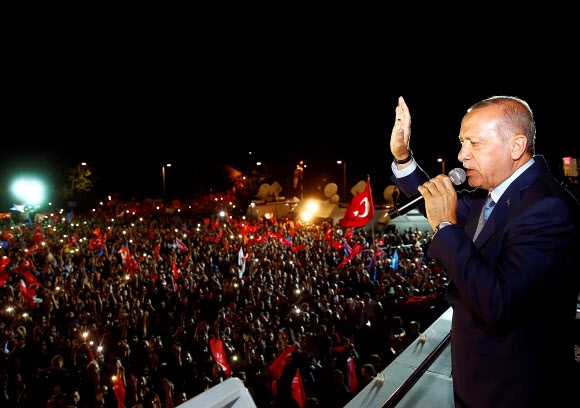 레제프 타이이프 에르도안 터키 대통령이 당선이 확정된 24일(현지시간) 밤 이스탄불의 대통령궁에서 승리를 자축하는 연설을 하며 지지자들을 향해 손을 흔들고 있다. 이스탄불 로이터 연합뉴스