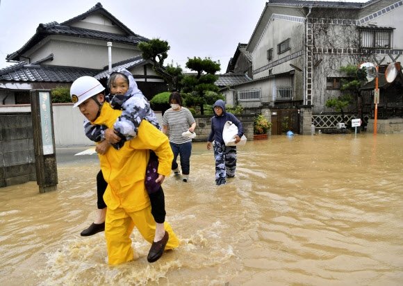 7일(현지시간) 폭우로 침수된 일본 남서부 오카야마 현 구라시키의 주택가에서 주민들이 구조대원의 안내를 받으며 안전지역으로 대피하고 있다. 일본 중부와 남서부 지역을 중심으로 이틀 전부터 기록적인 폭우가 이어지며 이날 오전까지 8명이 사망하고 최소 34명이 행방불명된 것으로 집계됐다.연합뉴스