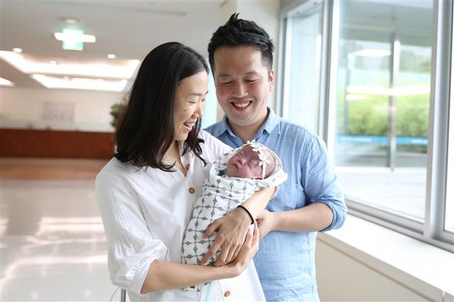 초미숙아로 태어난 사랑이의 어머니 이인선씨와 아버지 이충구씨가 사랑이를 품에 안고 활짝 웃고 있다.  서울아산병원 제공