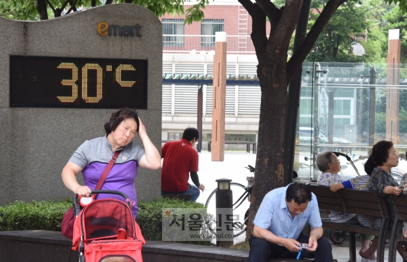 13일  전국 대부분 지역에 폭염 특보가 발효된 가운데  한 시민이 서울 성동구 이마트 앞에 설치된 온도계가 30도를 가르키고 있다. 한 시민이  흐르는 땀을  훔치며 걸어 가고 있다 2018.7.13최해국seaworld@seoul.co.kr