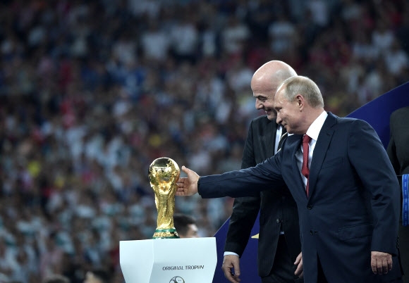 15일(현지시간) 러시아 모스크바 루즈니키 스타디움에서 열린 ‘2018 러시아 월드컵’ 결승에서 프랑스가 크로아티아를 꺾으며 우승을 차지한 가운데 시상식에 참석한 블라디미르 푸틴(오른쪽) 러시아 대통령이 우승 트로피를 만져보고 있다. 왼쪽은 지아니 인판티노 국제축구연맹(FIFA) 회장. EPA 연합뉴스