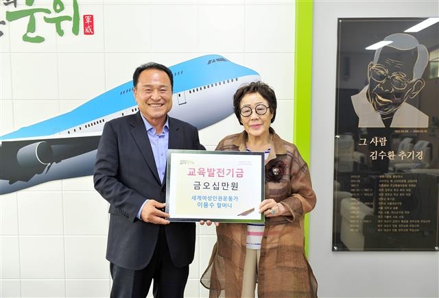 이용수(오른쪽) 할머니가 김영만 군위군수에게 장학금 50만원을 전달하고 있다.  군위군 제공