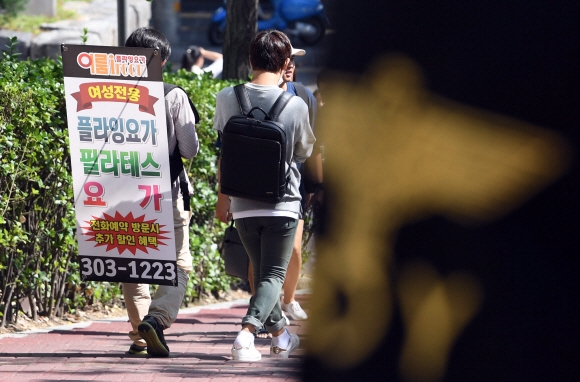 대학생 또래의 학생이 등에 휘트니스센터 광고판을 짊어지고 다니고 있다. 서울신문 DB