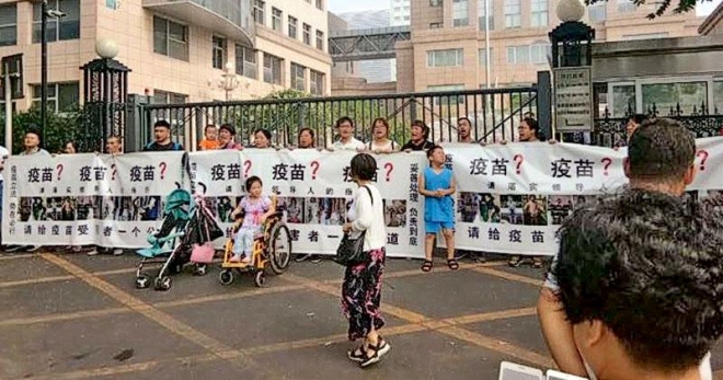 불량 백신에 항의하는 중국인들이 30일 베이징 보건당국 앞에서 ‘백신?’이라고 쓰인 플래카드를 들고 시위를 벌이고 있다. 출처: 홍콩 명보