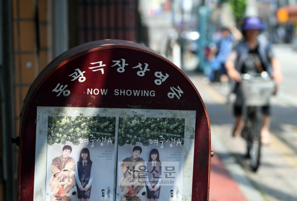 영화관 건물 밖에 ‘동광극장상영중’이라는 입간판이 세워져 있다.
