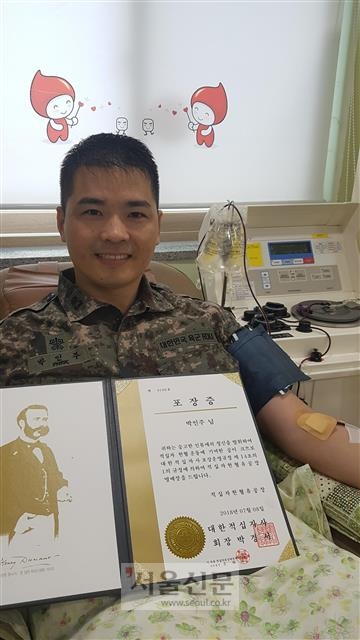 헌혈 100회를 달성해 받은 대한적십자사 유공 명예장을 들고 기뻐하는 박인주 소령.