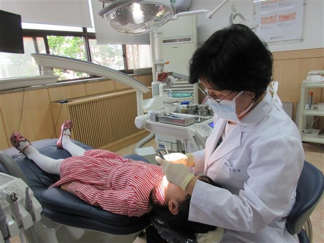 서울 광진구에서 실시하는 ‘아동 치과주치의 사업’의 하나로 치과주치의가 한 어린이를 치료하고 있다. 광진구 제공