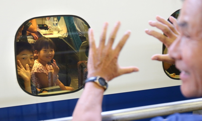 지난 15일 일본의 오봉 연휴를 지내고 귀경하는 손주들에게 할아버지가 손을 흔들어주고 있다. 나고야역에서 도쿄신문 제공