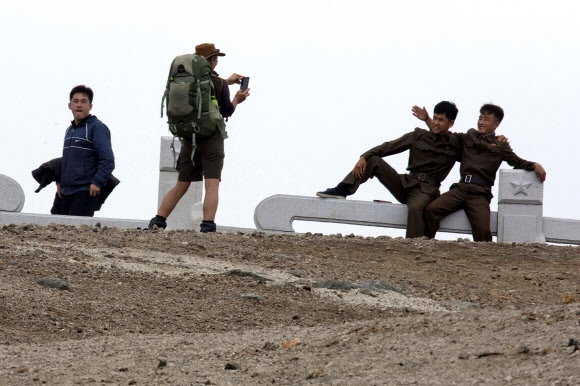 백두산 캠핑에 참석한 호주 관광객이 18일 백두산 정상에서 북한 군인들의 사진을 찍어주고 있다. 백두산 AP 연합뉴스  
