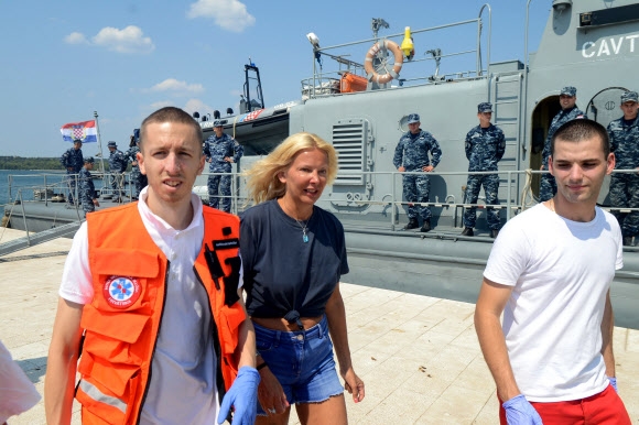 한밤중 유람선에서 추락해 바다에서 10시간을 버텨 구조된 영국 여성 케이 롱스태프(가운데)가 19일(현지시간) 크로아티아 풀라 항구에 도착해 자신을 구조한 해안경비대원들과 함께 멀쩡히 걸어나오고 있다. 풀라 AFP 연합뉴스