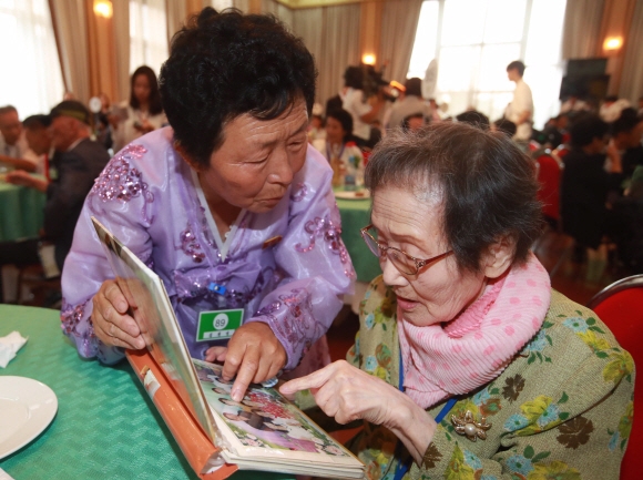 남측 한신자(오른쪽·99)씨가 북측 딸 김경영(71)씨가 가져온 가족사진을 보고 있다. 금강산 사진공동취재단