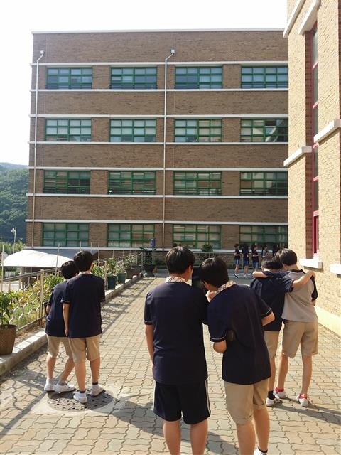 울산 천상중 1학년 학생들이 스마트폰과 태블릿PC 등의 높이 측정 애플리케이션을 활용해 건물의 부피를 직접 재 보고 있다.  천상중 제공