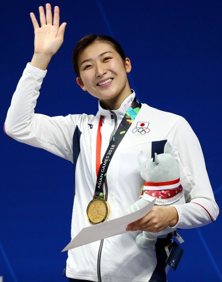 대회 최초로 4관왕에 오른 18세 여고생 이케에 리카코(일본)가 지난 21일 수영 여자 접영 100m 금메달을 목에 건 뒤 관중들에게 답례하고 있다. 자카르타 로이터 연합뉴스