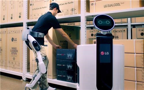 ‘LG 클로이 수트봇’을 착용한 작업자가 물류센터에서 상품을 쇼핑카트 로봇에 옮겨 담고 있는 모습. LG전자 제공