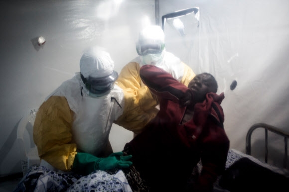 지난 15일(현지시간) 콩고민주공화국 북키부주 베니시의 임시 병원에서 보호복을 입은 의료진이 에볼라 환자를 들어올리고 있다.  베니 AFP 연합뉴스 