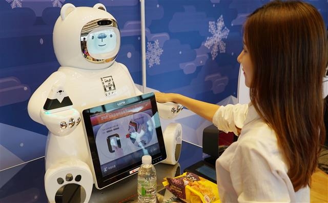 28일 서울 송파구 잠실 롯데월드타워에서 열린 세븐일레븐의 핸드페이 탑재 AI 결제 로봇 ‘브니’ 시연회에서 한 고객이 브니의 왼손에 손바닥을 마주 대고 핸드페이로 상품을 구매하고 있다. 세븐일레븐 제공