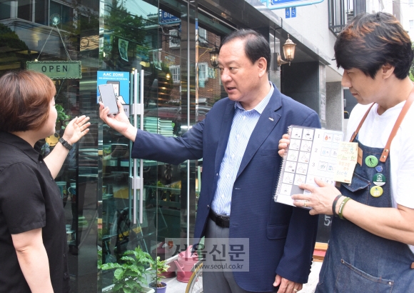 유동균(가운데) 서울 마포구청장이 28일 보완대체의사소통(AAC) 시스템을 적용한 성산1동 주민센터 인근 한 커피숍에서 관계자들과 스마트폰으로 말없이 주문하는 방법에 대해 설명을 들은 뒤 시연하고 있다. 최해국 선임기자 seaworld@seoul.co.kr