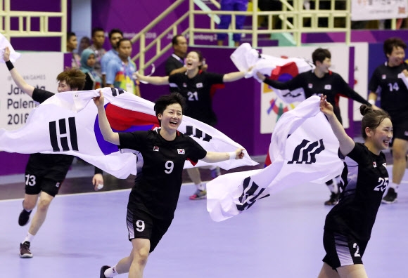 한국 여자 핸드볼 대표팀 선수들이 30일 인도네시아 자카르타 포키 치부부르 경기장에서 열린 자카르타·팔렘방아시안게임 결승전에서 중국을 29-23으로 꺾고 금메달을 따낸 뒤 태극기를 들고 경기장을 누비고 있다.  자카르타 연합뉴스