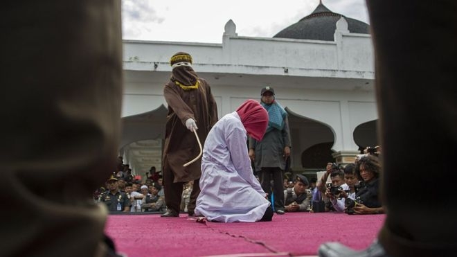 지난 2015년 6월 12일 인도네시아 아첸주의 한 광장에서 정부 관리가 여인을 상대로 공개 태형을 집행하고 있다. AFP 자료사진 