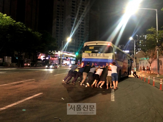 지난달 30일 오후 9시 20분경 부산 해운대구 시외버스터미널 앞 도로에서 유턴을 하다 고장난 시외버스 뒤에서 시민들과 경찰이 힘을모아 가장자리로 옮기고 있다. (부산지방경찰청 제공)